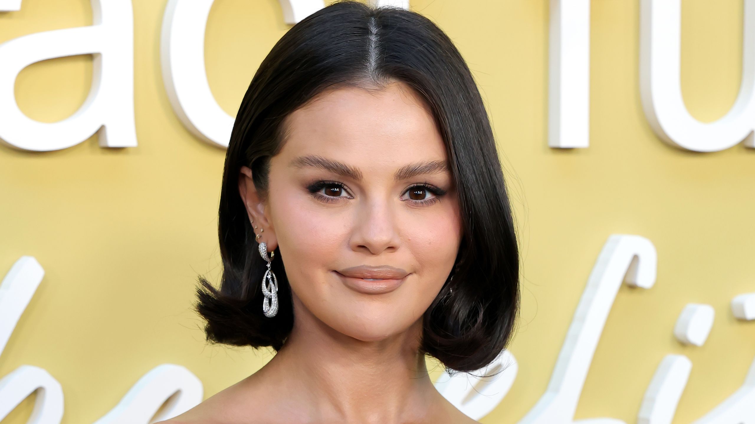 Selena Gomez poses at an event in a lavenderpink dress. Her hair is styled in a bob.